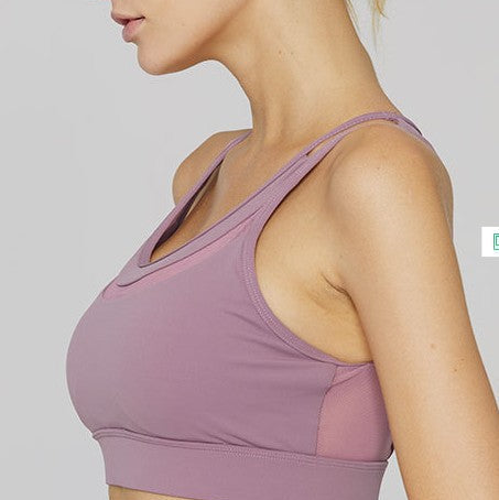 Woman wearing a purple sports bra against a plain background